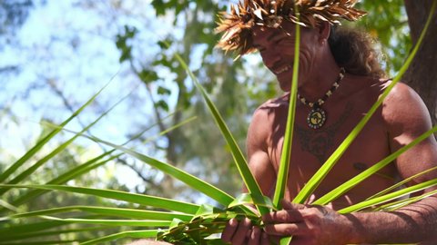 Happy traditional Tahitian man performing hat making, on tourist tour in Bora Bora, Tahiti. French Polynesia. Exotic travel vacation getaway, romantic honeymoon destination.