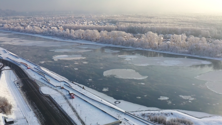 Aerial shot of beautiful winter embankment with ice is forming on the river. Ice flows form an intricate geometric pattern. High quality.