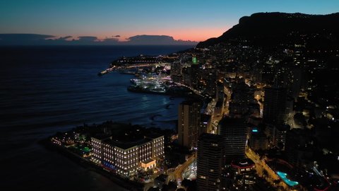 France, Monaco, Larvotto, right to left night drone aerial view with illuminated buildings.