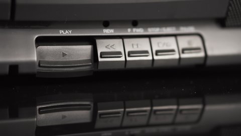 Play button on an old black audio cassette player. The man presses the play button with his finger. Close-up buttons. Old technologies of the previous generation. Analog equipment