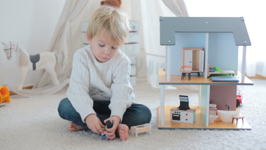 Cute toddler child, playing with toys at home in sunny room