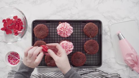 Time lapse. Flat lay. Step by step. Decorating red velvet cupcakes with chocolate red hearts and kisses.