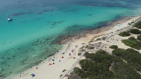4k footage from a drone of a beach with people, umbrellas and turquoise water.