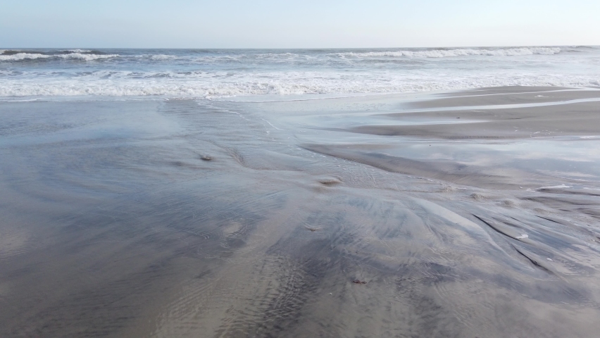 Water from the ocean washing up onto a wet sandy beach
