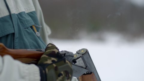 Hunter reloading cartridge in field. Smoke from the trunks of smooth-bore hunting rifle after firing. Slow motion 240 fps