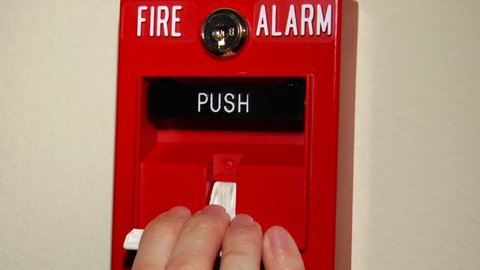 Close up of someone pulling a fire alarm