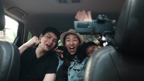 Friend group making selfie vlog video together in car during traveling trip.