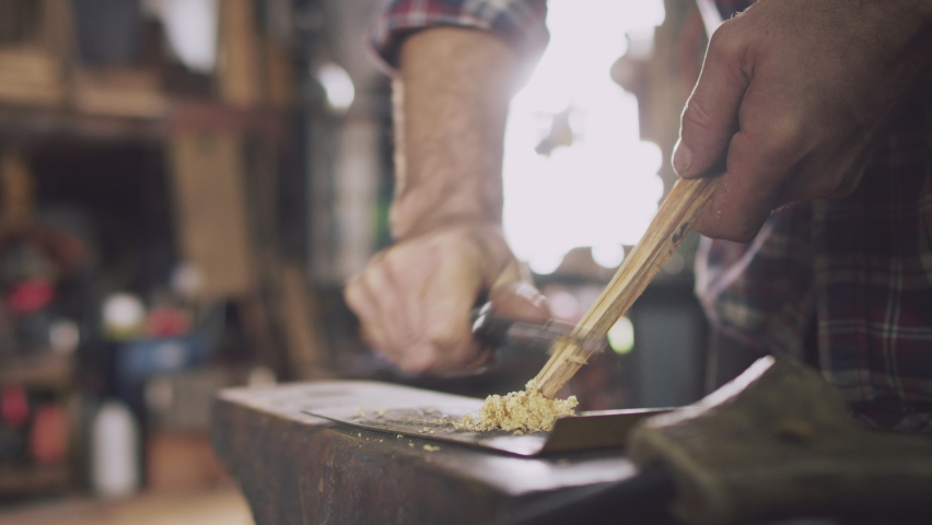 Male Blacksmith Making Wood Shavings For Kindling On Anvil To Light Forge