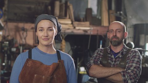 Portrait Of Male And Female Blacksmiths With Folded Arms Standing In Forge