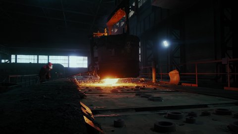 Metallurgist Works in A Steel Plant. Hot Molten Liquid Metal Pouring From Furnace to the Press Moulds at Metallurgical Plant. Factory Worker controls the process.Heavy Industry Manufacture.Slow Motion