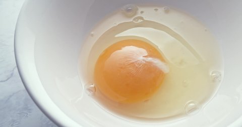 Man Drops Two Eggs into A White Bowl. Close up, minimal, stylish cooking concept