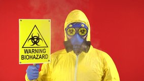 Man in Protective Chemical Suit, Mask and Banner in Hands. Biological Protection. Smoke Around Man. Isolate, Studio. Protection concept, radioactive hazard concept.