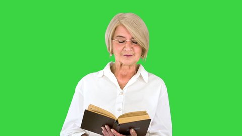 Beautiful senior woman reading aloud from a book on a Green Screen, Chroma Key.