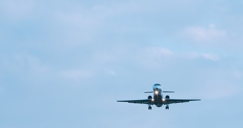 Business jet is landing at evening sky. Private business airplane flying above overhead with bright lights. Slow motion