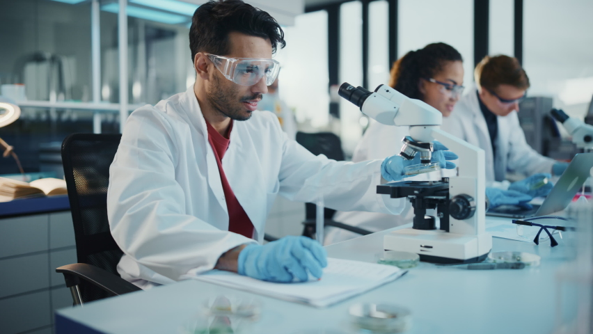 Modern Medical Research Laboratory: Portrait of Latin and Black Young Scientists Using Microscope, Digital Tablet, Doing Sample Analysis, Talking. Diverse Team of Specialists work in Advanced Lab Royalty-Free Stock Footage #1065136732