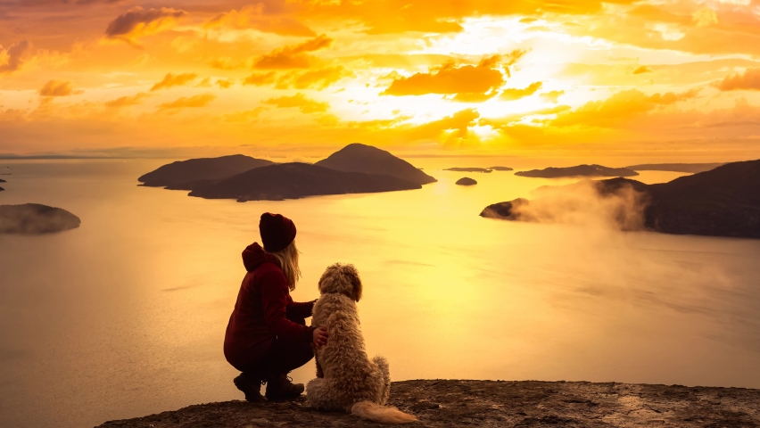 Adventurous Girl Hiking on top of a Mountain with a dog during a colorful sunset. Tunnel Bluffs Hike, near Vancouver and Squamish, British Columbia, Canada. Cinemagraph Continuous Loop Animation.