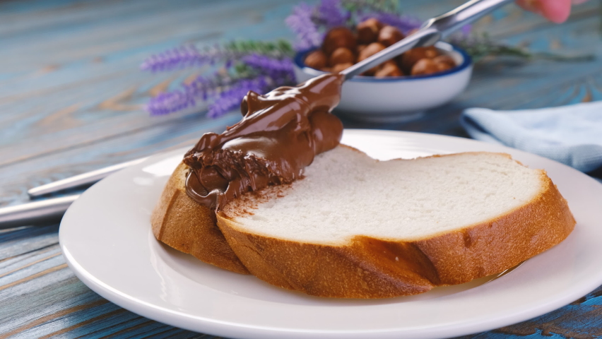 Spreading hazelnut cream on white bread slice, chocolate nut butter on school lunch toast Royalty-Free Stock Footage #1065144547