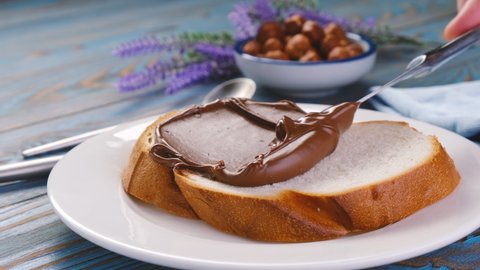 Spreading hazelnut cream on white bread slice, chocolate nut butter on school lunch toast