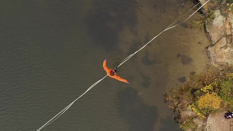 Man balancing on slackline over the river. Falling from slackline. Slowmotion footage
