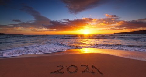 Sea sunrise with colorful cloudscape on sandy beach and text over sand 2021 new year