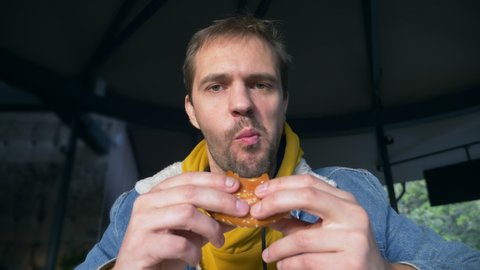 portrait of angry man eating hamburger at fast food cafe.