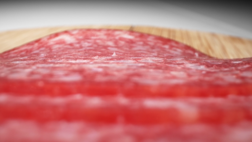 Extreme close-up, detailed. salami sausage cut into thin pieces on a wooden board | Shutterstock HD Video #1065153082