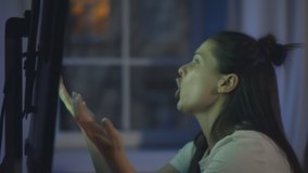 Angry woman watching sports on television sitting in front of tv screen. Side view of anxious emotional female watching football on tv and yelling because of her favorite team losing - Powered by Shutterstock - Get 15% off with code: PIKWIZARD15