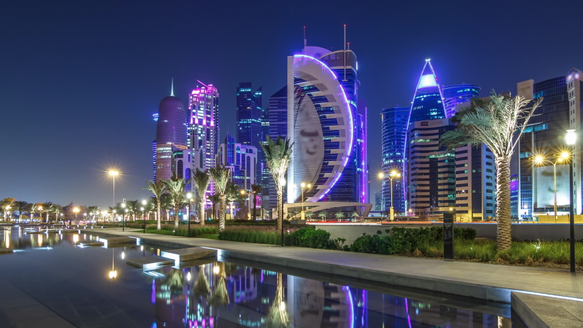 The skyline of Doha by night with starry sky seen from Park timelapse hyperlapse, Qatar. Illuminated skyscrapers and towers reflected in water of fountain Royalty-Free Stock Footage #1065168904