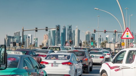 Doha skyline and traffic jam on the intersection timelapse as viewed from corniche in Doha, Qatar, Middle East. Cars in front of traffic lights