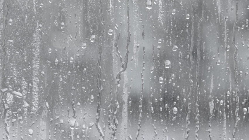 Splashes of water droplets on the glass. Window on a rainy day.Wet glass with large drops of water or rain. Video of water droplets on a clear glass surface during heavy rain. Dripping water Royalty-Free Stock Footage #1065173404