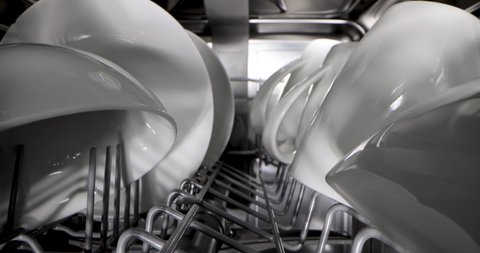 household appliances - sliding inside dishwasher. rack with clean white dishware