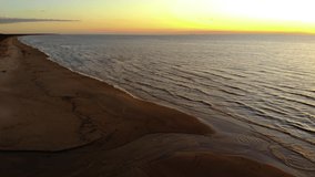Scenic establishing shot: Beautiful evening beach with vivid yellow sky after sunset aerial