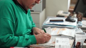 Senior financial worker in glasses sitting at the table, reading contract and putting his signature on sheet of paper. Process of signing agreement in bank department - Powered by Shutterstock - Get 15% off with code: PIKWIZARD15