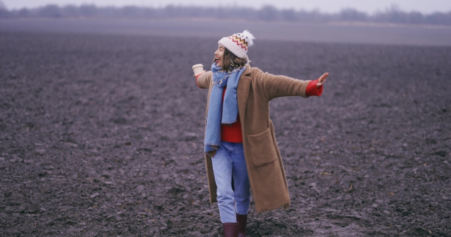 Beautiful young woman in winter clothes enjoying winter time on the field. Nature enjoyment and freedom lifestyle concept. Medium handheld video