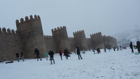 Avila, Spain; 01.08.2021: People sledding on the north side of the rampart wall of Avila
