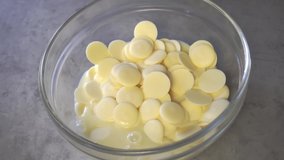 Pieces of white chocolate are melting in milk, stirring in a plate