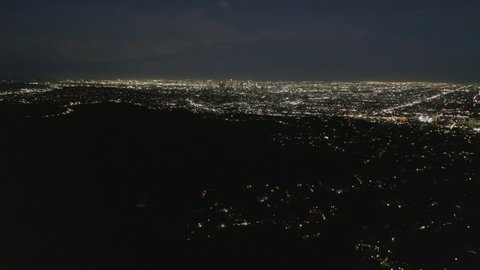 AERIAL: Slow Tilt Move over Hollywood Hills at Night revealing Los Angeles City Lights 