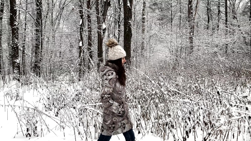 Woman walks through a winter forest with snow covered trees. Lifestyle, happiness, vacation concept