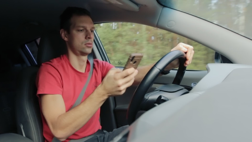 Driver uses mobile phone to read messages and drive at speed while driving on road. Accident and danger of looking at smartphone. Royalty-Free Stock Footage #1065219700