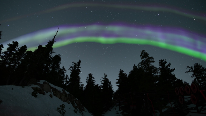 Aurora Green and Purple Arch Above Snow Covered Alpine Mountain Forest Loop