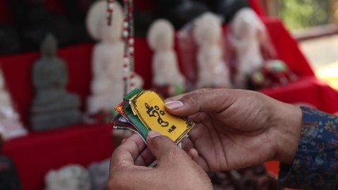 A person is shopping at the road side tibetan souvenir shop at Sarnath in Varanasi,India with selective focus. Decorative items are being sold like flags, garlands, and bags in the tibetan market. 
