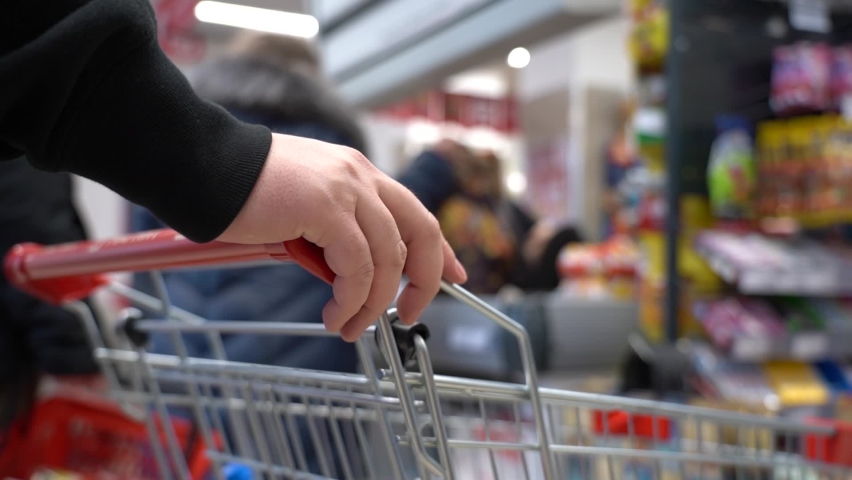 Film grain. A Man With a Shopping Cart Stands in Line at the Checkout Counter and Nervously Taps his Finger on the Cart. Supermarket Shopping Concept. Selective Focus. Faceless. Royalty-Free Stock Footage #1065224134