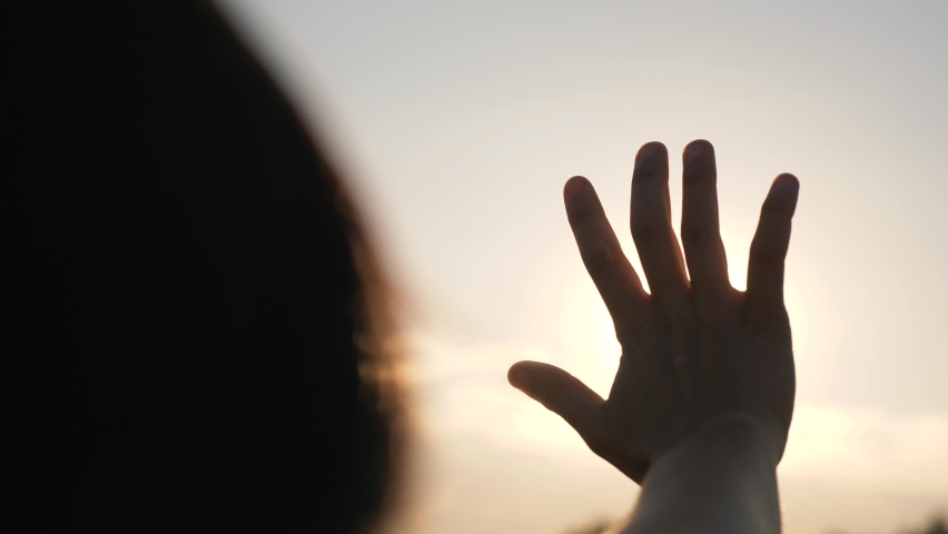 Hand of happy girl at sunset. Sunset between the hands of girl. Happy girl with long hair dreamily stretches out her hand to the sun. Child's dream hand to the sun. happy family concept Royalty-Free Stock Footage #1065225805