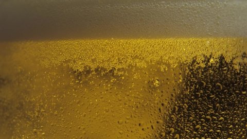 Beer pouring and splashing in slow motion. Freshness and froth. Pouring Beer Into Glass Macro Video. Cold Light Beer in a glass with water drops