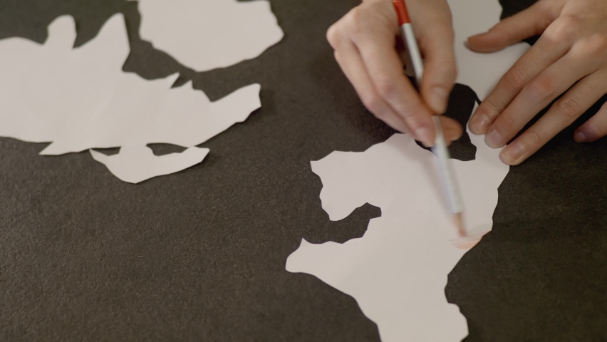 Marking Coronavirus infected regiones with red pencil,improvised paper model of continents.Tender woman hands paint with red colour means danger.Lots of covid-19 cases over the world.Virus spreading