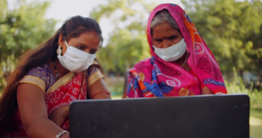 Slow-motion of senior aged woman learns from younger with surgical face masks outdoors using laptop computer technology digital device to communicate with friends family voice video call