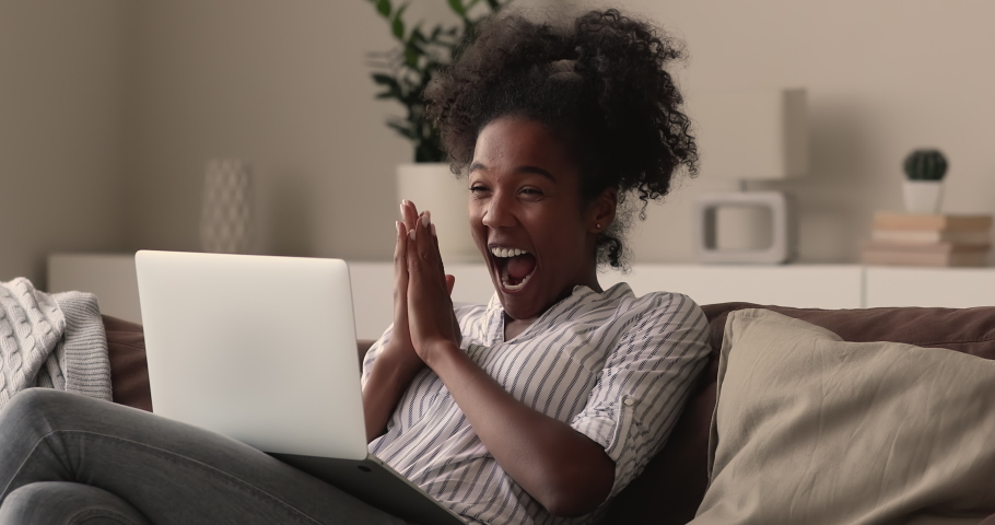Young african woman sit on couch read great unbelievable fantastic news on laptop feels happy celebrate success in online lottery, betting auction. Student get scholarship or female got hired concept Royalty-Free Stock Footage #1065237649