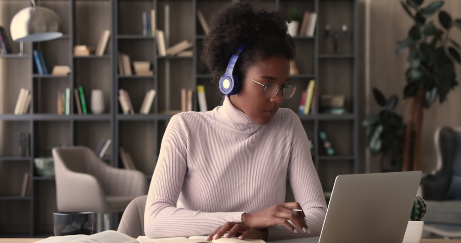 African woman student e-learn prepare for university exam, admission to college remotely by online course, listen audio lesson through headphones, writes notes. Self-education using internet concept | Shutterstock HD Video #1065237730