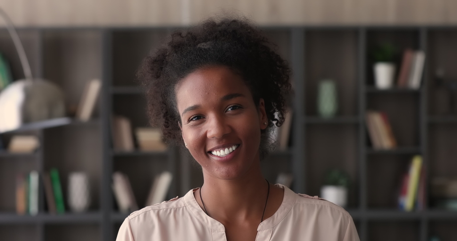 Head shot african staff member pose in office alone smile look at camera. Happy employed female, professional occupation person, portrait of 25 attractive lady with charming perfect toothy white smile | Shutterstock HD Video #1065237820