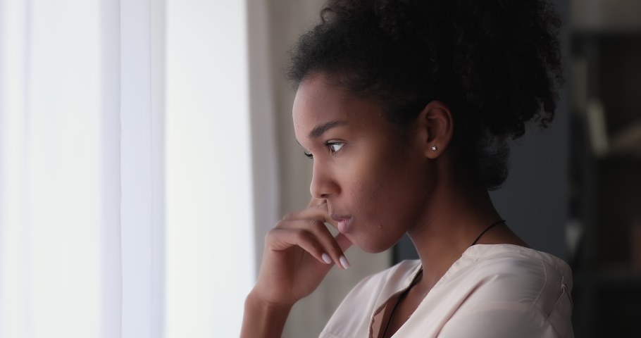 Young african woman standing indoor looking out window thinking, lost in sad thoughts having personal life or health concerns feels upset. Break up, divorce, psychological disorder, loneliness concept Royalty-Free Stock Footage #1065237835